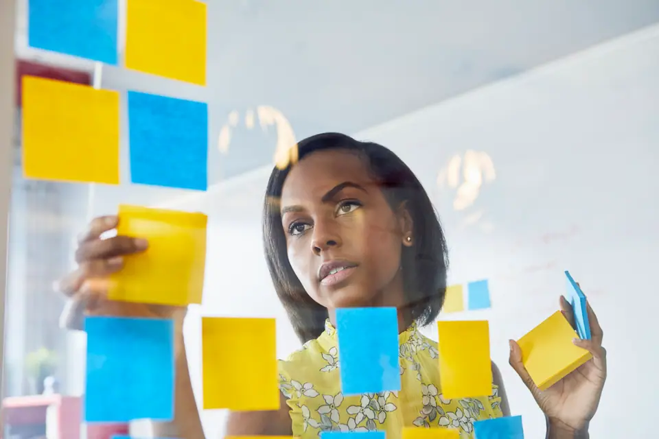 A business owner organizes her sales pipeline on sticky notes